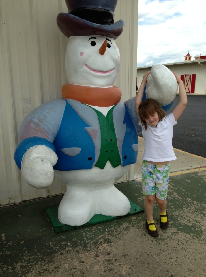 A getting her picture taken with a snowman in June.  Only in Ohio.